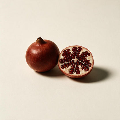 Whole and halved pomegranate (Punica granatum) on a seamless off-white background